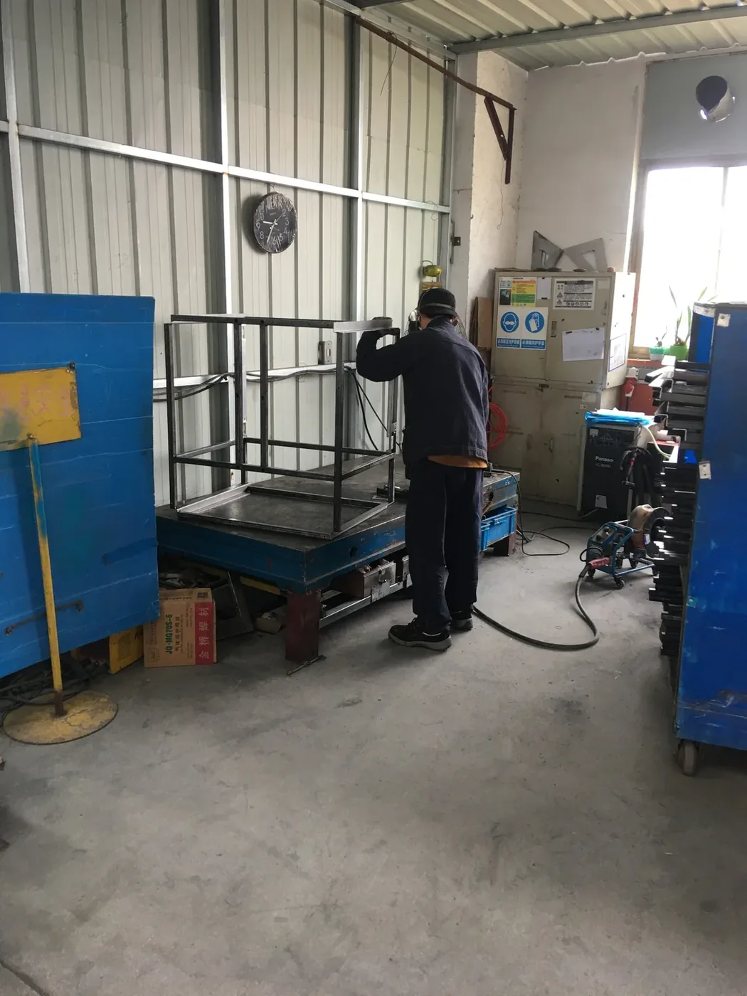 Welder assembling a 3D printer frame on a fabrication platform